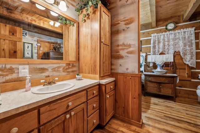 bathroom featuring hardwood / wood-style floors, wooden walls, beamed ceiling, vanity, and wooden ceiling