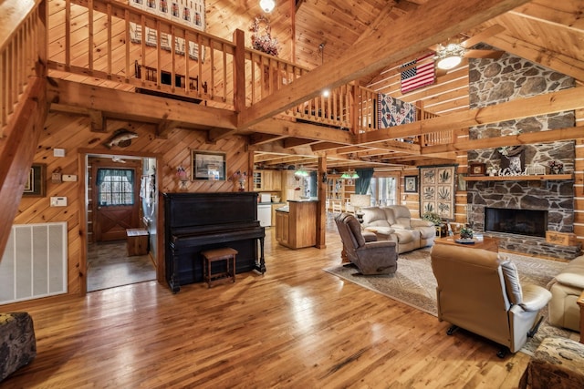 living room featuring beam ceiling, wood-type flooring, high vaulted ceiling, and wooden walls