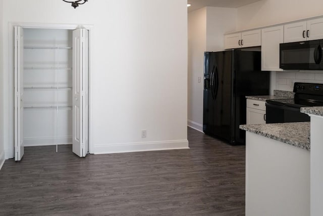 kitchen with white cabinetry, light stone countertops, black appliances, dark hardwood / wood-style flooring, and decorative backsplash