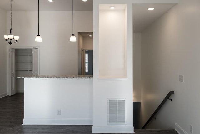 kitchen featuring hanging light fixtures, dark hardwood / wood-style flooring, light stone counters, and kitchen peninsula