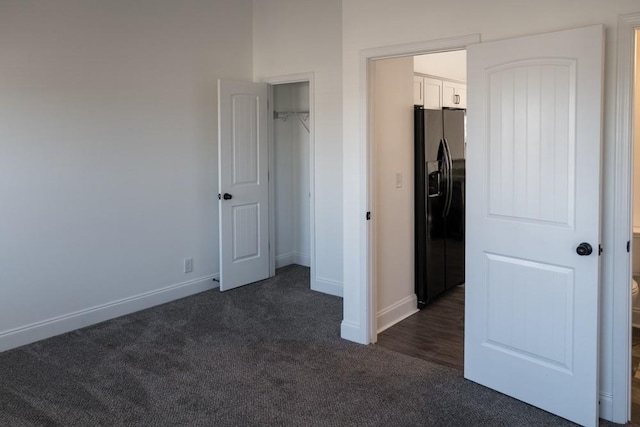 unfurnished bedroom with black fridge with ice dispenser, dark carpet, and a closet