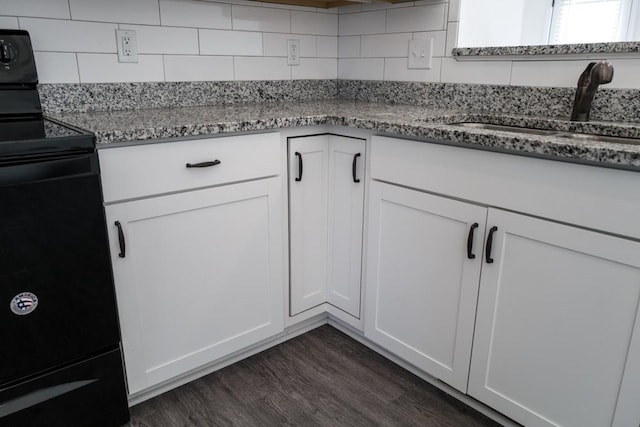 kitchen featuring sink, white cabinetry, dark hardwood / wood-style floors, black range with electric stovetop, and light stone countertops