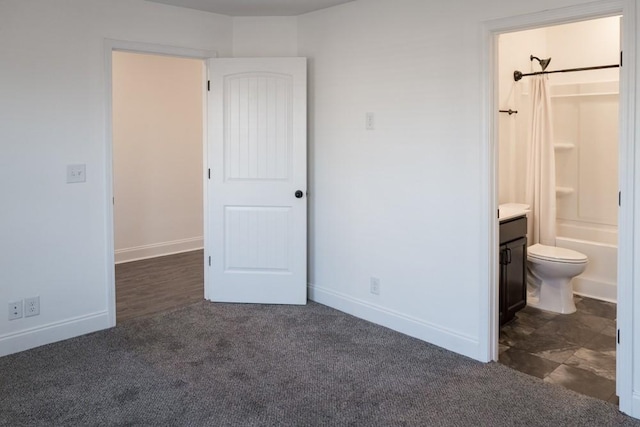 unfurnished bedroom with dark carpet and ensuite bath