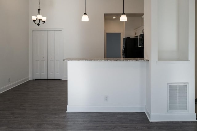 kitchen featuring black refrigerator, dark hardwood / wood-style flooring, hanging light fixtures, and white cabinets