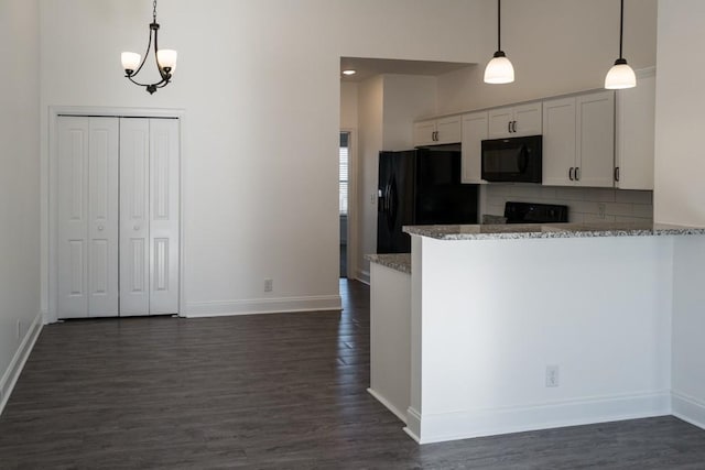 kitchen featuring white cabinets, dark stone countertops, decorative light fixtures, and black appliances