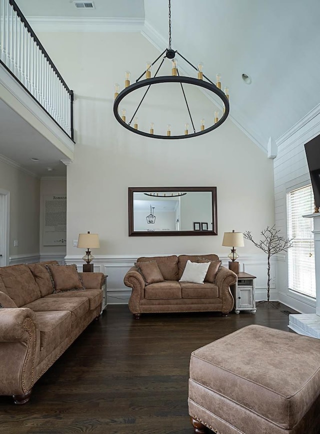 living room featuring an inviting chandelier, ornamental molding, dark hardwood / wood-style floors, and a high ceiling