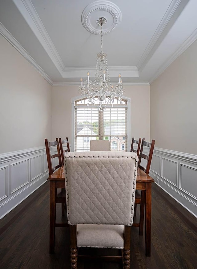 dining room with dark hardwood / wood-style flooring, a tray ceiling, crown molding, and a chandelier