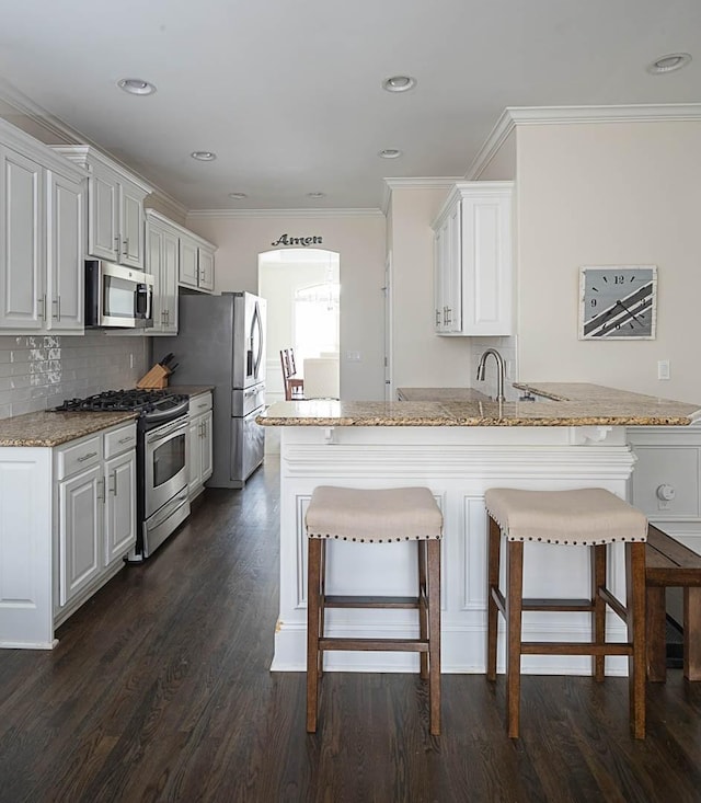 kitchen with white cabinetry, dark hardwood / wood-style flooring, kitchen peninsula, and appliances with stainless steel finishes