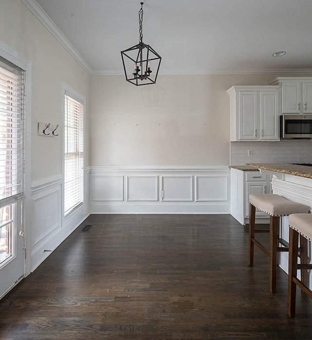 unfurnished dining area featuring crown molding, dark hardwood / wood-style floors, and a notable chandelier