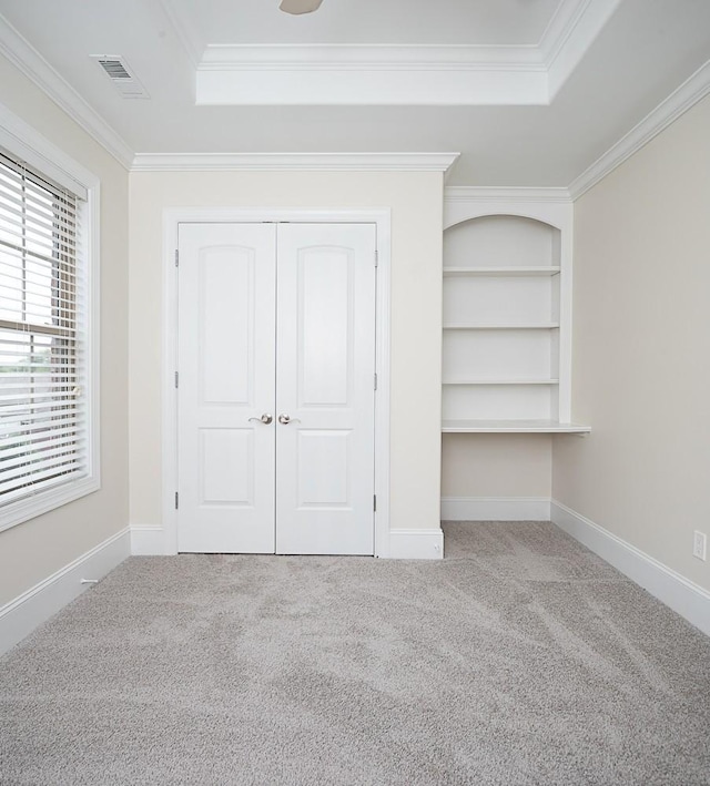 unfurnished bedroom featuring crown molding, a tray ceiling, and light carpet