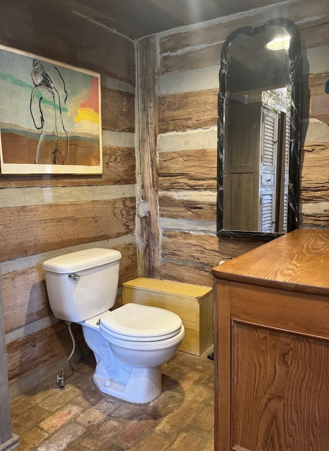 bathroom featuring wooden walls and toilet