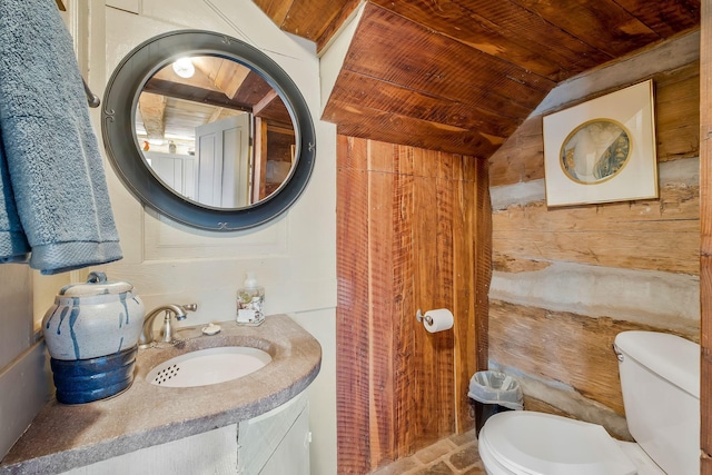 bathroom with wooden walls, lofted ceiling, vanity, wood ceiling, and toilet