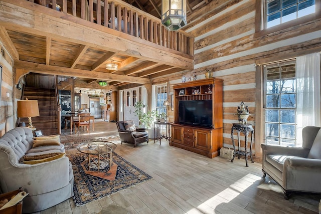 living room with plenty of natural light, a towering ceiling, hardwood / wood-style floors, and wood walls