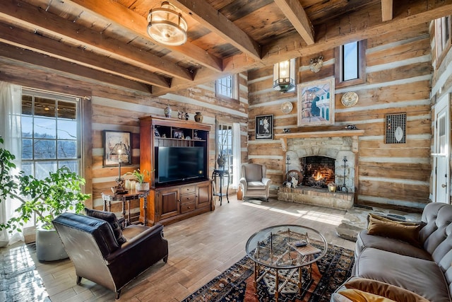 living room featuring wood walls, beam ceiling, a stone fireplace, and wooden ceiling