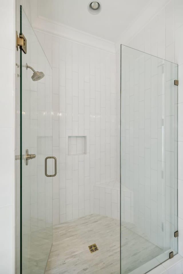 bathroom with a shower with door and crown molding