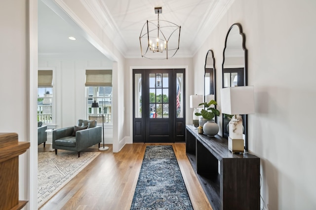 foyer featuring an inviting chandelier, hardwood / wood-style flooring, and ornamental molding