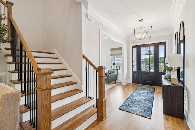 foyer entrance with a notable chandelier, crown molding, and light hardwood / wood-style flooring