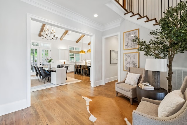 living area with light wood-type flooring, a notable chandelier, crown molding, beam ceiling, and french doors