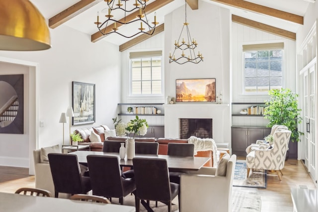 dining area with a notable chandelier, a fireplace, lofted ceiling with beams, and light hardwood / wood-style floors