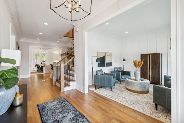 living room with crown molding, wood-type flooring, and a chandelier