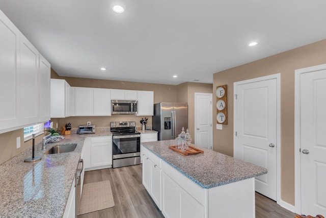 kitchen featuring sink, light wood-type flooring, a kitchen island, stainless steel appliances, and white cabinets