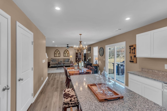 kitchen with a chandelier, light stone countertops, light hardwood / wood-style flooring, and white cabinets