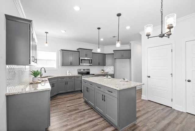 kitchen with appliances with stainless steel finishes, a center island, sink, and gray cabinetry