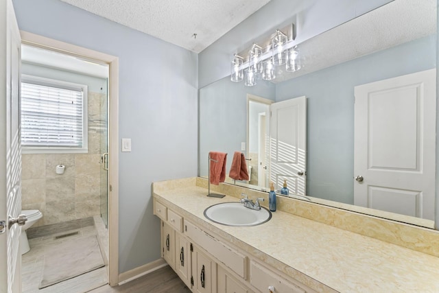 bathroom with walk in shower, toilet, a textured ceiling, vanity, and hardwood / wood-style flooring