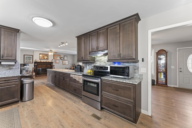 kitchen with stainless steel appliances, light hardwood / wood-style flooring, dark brown cabinetry, and decorative backsplash