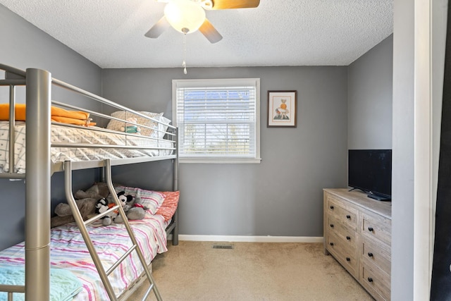 bedroom featuring ceiling fan, light colored carpet, and a textured ceiling