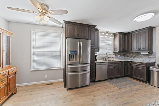 kitchen with backsplash, plenty of natural light, stainless steel appliances, and light wood-type flooring