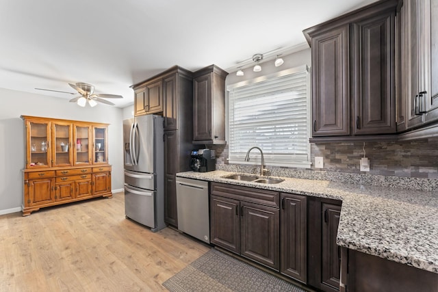 kitchen featuring dark brown cabinetry, sink, light stone countertops, and appliances with stainless steel finishes