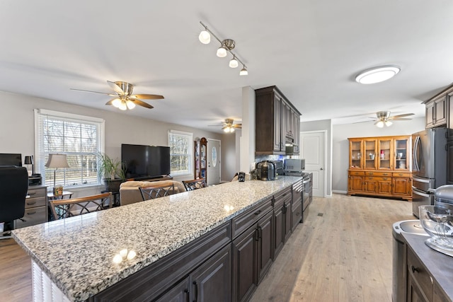 kitchen with light stone counters, a wealth of natural light, light hardwood / wood-style flooring, and appliances with stainless steel finishes