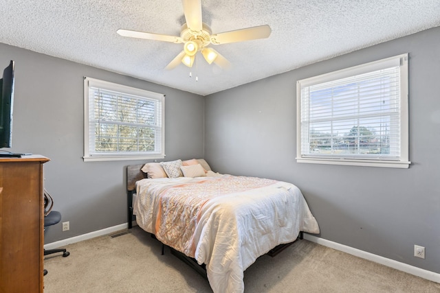 carpeted bedroom featuring multiple windows, a textured ceiling, and ceiling fan