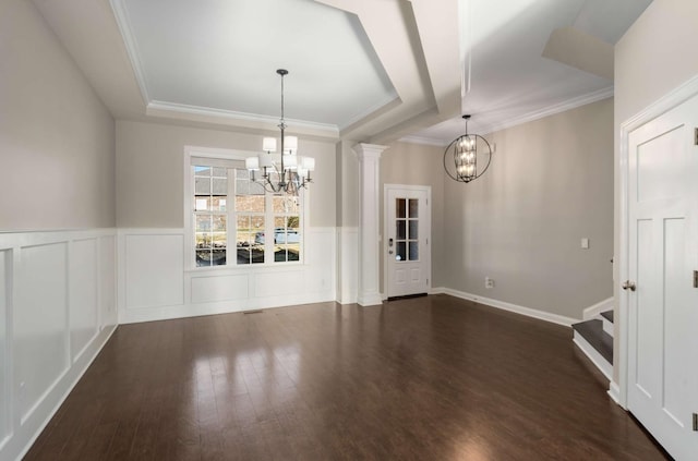 unfurnished dining area with an inviting chandelier, a tray ceiling, dark hardwood / wood-style flooring, and ornate columns