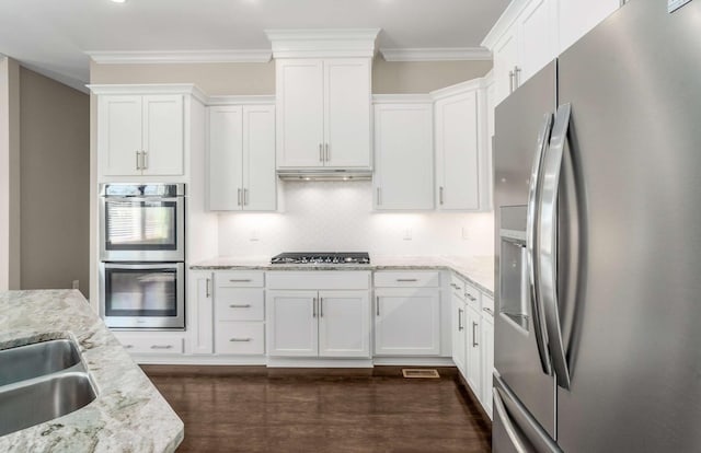 kitchen with crown molding, appliances with stainless steel finishes, backsplash, light stone countertops, and white cabinets