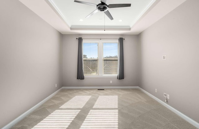 spare room with crown molding, a tray ceiling, light carpet, and ceiling fan