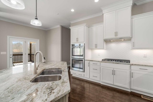 kitchen with sink, white cabinets, backsplash, hanging light fixtures, and stainless steel appliances