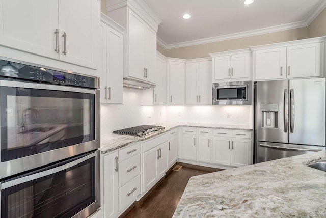 kitchen featuring light stone countertops, ornamental molding, stainless steel appliances, and white cabinets