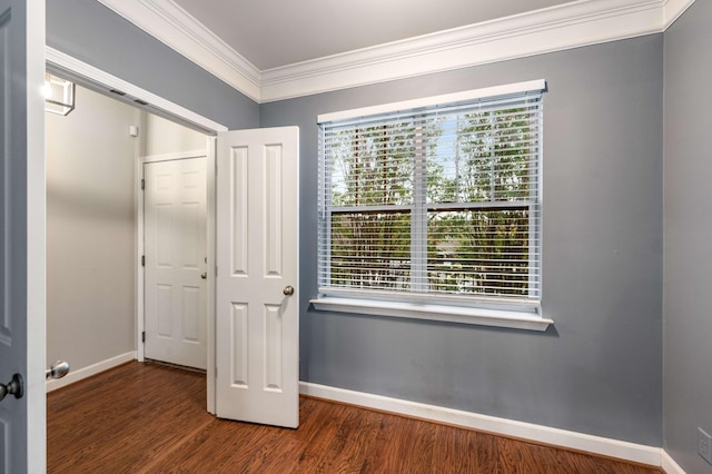 unfurnished bedroom featuring crown molding, multiple windows, dark wood-type flooring, and a closet