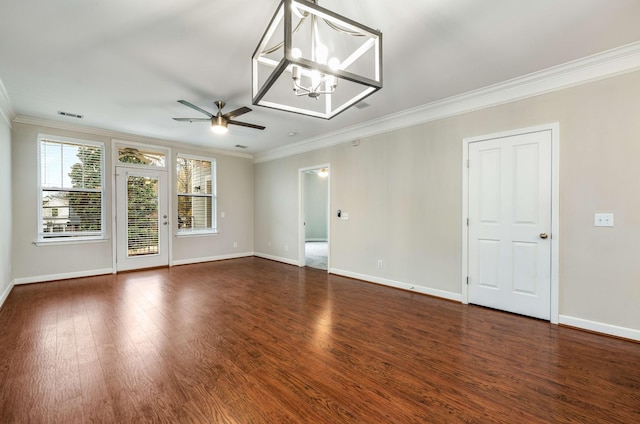 spare room featuring dark wood-type flooring, ornamental molding, and ceiling fan with notable chandelier