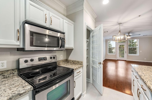 kitchen with white cabinets, hanging light fixtures, stainless steel appliances, crown molding, and light stone countertops