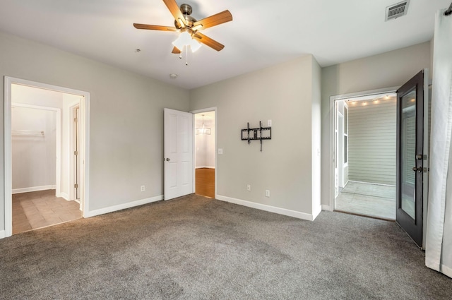 unfurnished bedroom featuring connected bathroom, carpet floors, and ceiling fan