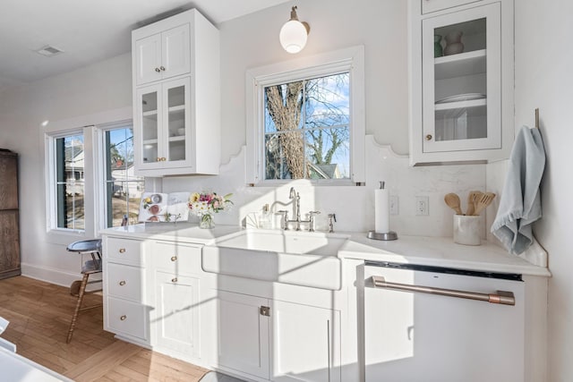 kitchen with white cabinetry, white dishwasher, sink, and a wealth of natural light