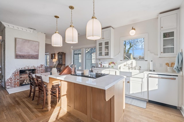 kitchen with sink, white cabinetry, decorative light fixtures, a center island, and dishwasher