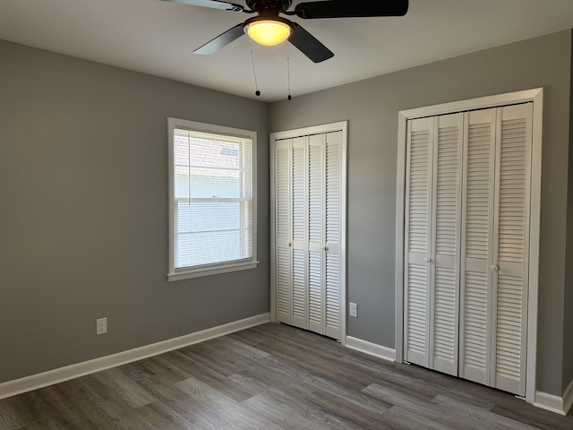 unfurnished bedroom featuring ceiling fan, multiple closets, and light wood-type flooring