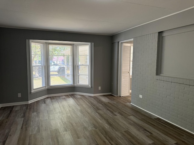 empty room featuring brick wall and dark hardwood / wood-style flooring