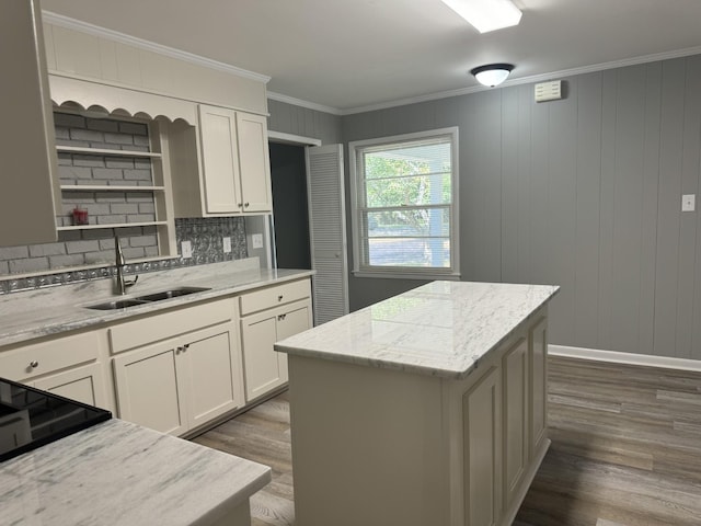 kitchen with sink, crown molding, light stone countertops, and a center island