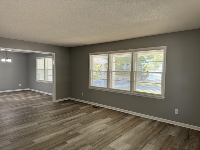 spare room with dark hardwood / wood-style flooring, a textured ceiling, and a chandelier