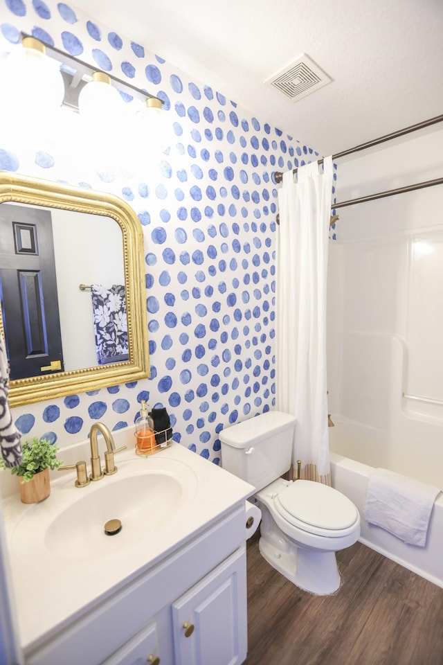 full bathroom with shower / tub combo, hardwood / wood-style floors, vanity, a textured ceiling, and toilet